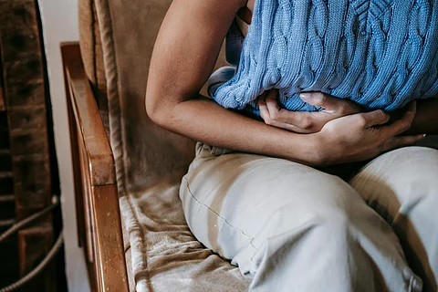 a women holding her stomach due to bacteria infection sitting in the chair