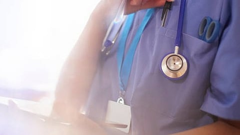 A health care professional with a stethoscope is visible in blue scrubs.