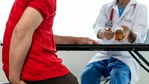 A person in a red shirt receiving some medication from a healthcare professional.