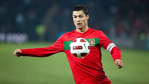 An image of Christiano Ronaldo in a red jersey kicking a football during a game.