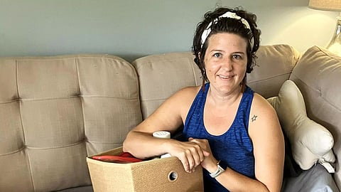 Erica Hayes holds a box where she keeps the medical supplies she needs to manage her long-covid symptoms, which include chronic fatigue, an irregular heart rate, low blood pressure, hives, migraines, and internal tremors. (Sarah Boden for KFF Health News)