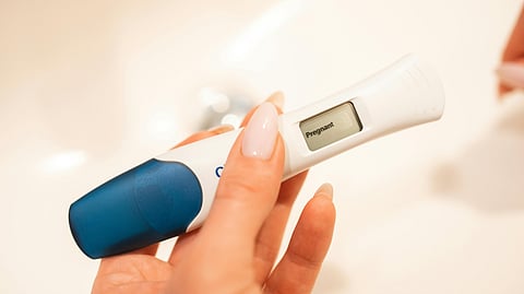 A hand gripping an electronic thermometer, indicating preparation for a temperature reading.