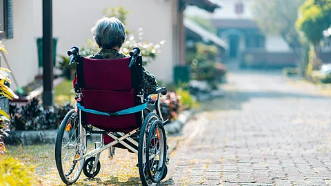 Elderly person in a wheelchair outdoors, symbolizing Alzheimer's care and treatment advancements.