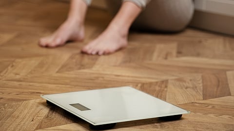 Woman with eating disorder crying next to a scale