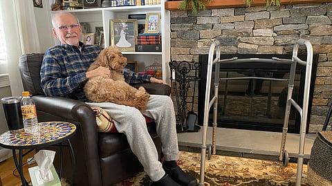 A man is sitting on a couch with his dog.