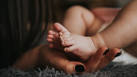 A close-up of a woman’s hand cradling a tiny baby's feet.