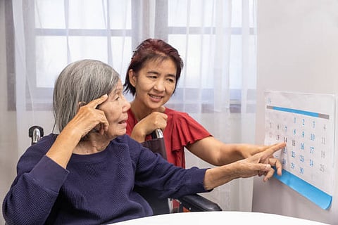 An elderly woman and a young woman sit together at a table, engaged in conversation and sharing a warm moment.