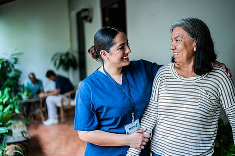A nurse engages in conversation with an elderly woman, providing care and support in a warm, compassionate setting.