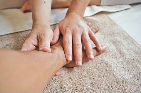 A person receiving a hand massage and the occupational therapist's hands in action.