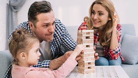 Family playing wooden blocks with their kid.