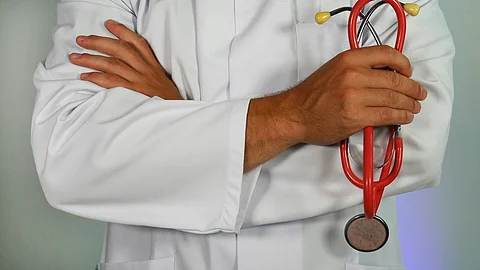 A healthcare professional in a white coat is holding a stethoscope, ready for a medical examination.