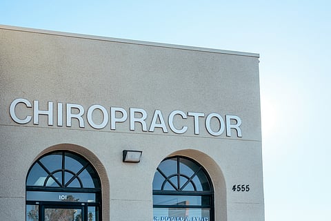 A building with two arched windows and a sign that says chiropractor.