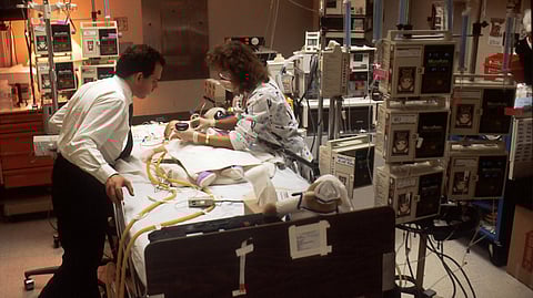 A child is lying down on a hospital bed connected to medical devices.