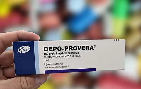 A person holding a box of Depo-Provera, an injectable contraceptive used for birth control.