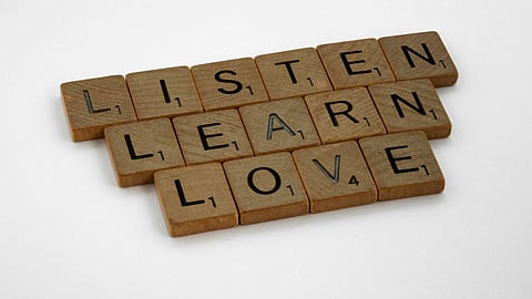 Brown wooden blocks with words "Listen, Learn, Love" on white surface
