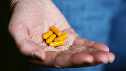 yellow medication pill on persons hand