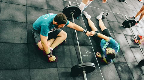 man fist bump to man laying on ground after exercise