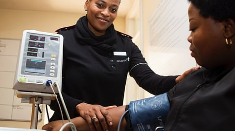 A nurse measures a patient's blood pressure using a sphygmomanometer in a clinical setting.