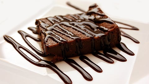 Close-up of a rich, chocolatey brownie smothered in chocolate sauce.