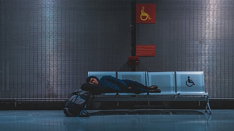 A man sleeping on a bench for handicapped people in a public place like train station.