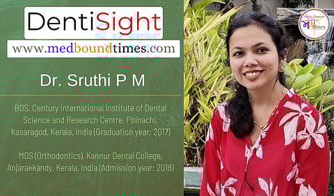 A picture of a Dr. Sruthi P M in a red top with an artificial pond and waterfall in the background.