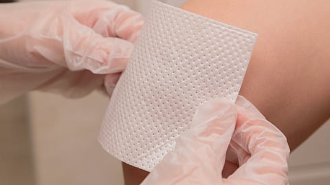 A close-up image of a tissue paper being placed on the knee.