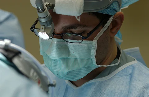 A surgeon in an operation theatre looking down at the surgical field.