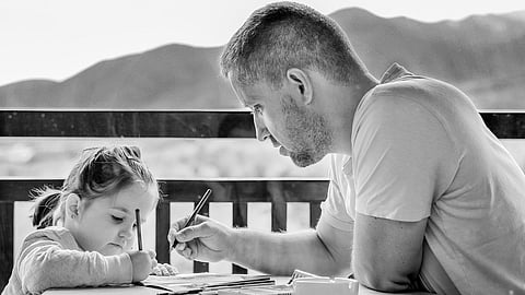 Black and white image of a father and daughter working on a project together.