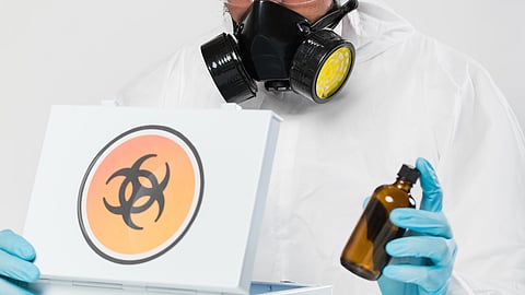 A person wearing a protective gear, including gas mask and gloves is handling a hazardous material.