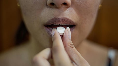 A woman consuming a white pill.