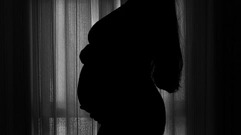 A pregnant woman standing in front of a window