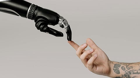 The image represents a robot and a human hand touch each other at fingertip.