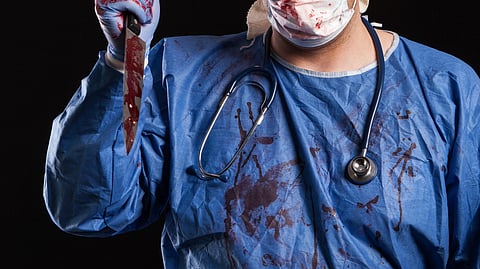Young man dressed up in doctor costume for halloween over black background. Portrait of doctor with evil face.