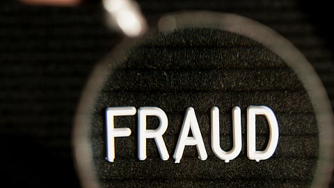 Fraud word in a magnifying glass and blurred effect