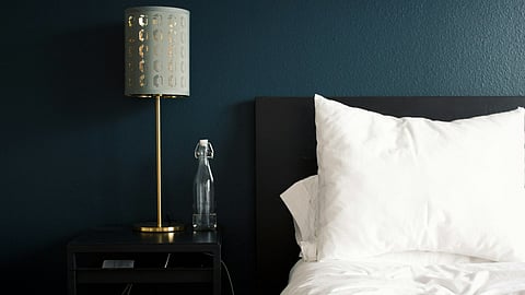 gray table lamp beside white bed pillow