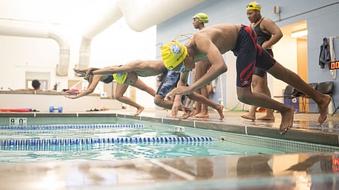 The image shows a group of swimmers preparing to start a race or training session.
