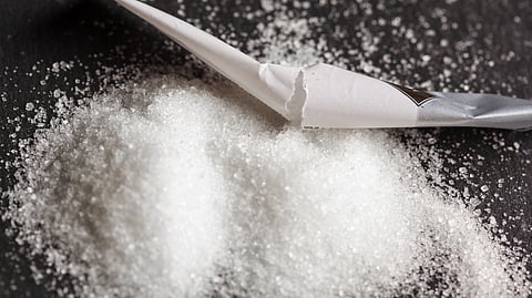 A white substance spilled from a small paper packaging on a surface.