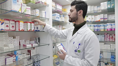 A pharmacist in a pharmacy handling medicines.