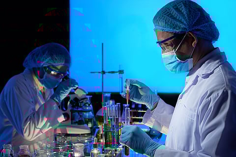 Scientists working in a lab surrounded by dim light and equipment.