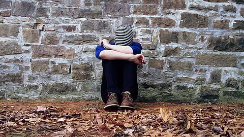 A person sitting against a stone wall.