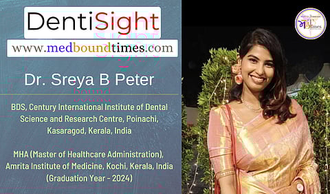 Dr. Sreya in a peach and gold colored saree is smiling standing outdoors in front of green bushes.