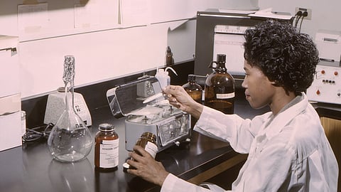 A woman sitting in front of a table, working on mixing various drugs to study their results.