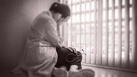 Depressed female doctor sitting in despair near a hospital window