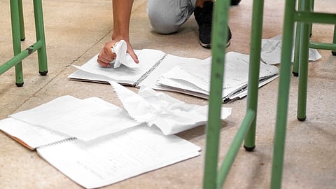 A student collecting the papers from the ground