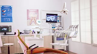 Inside of a dental clinic showing a dental chair and equipment.