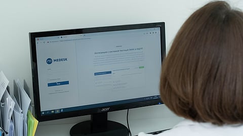 A woman sitting at a desk looking at a computer screen