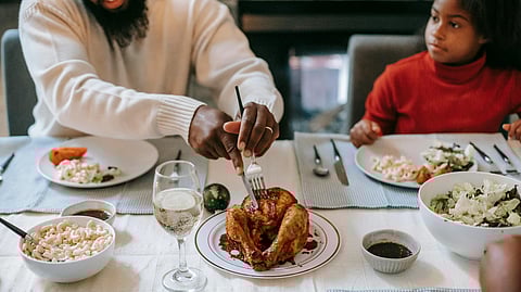 A man and kid having chicken in dinning table