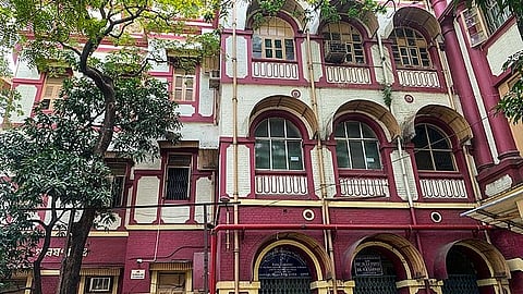 A maroon-colored multi-story building with arched windows.