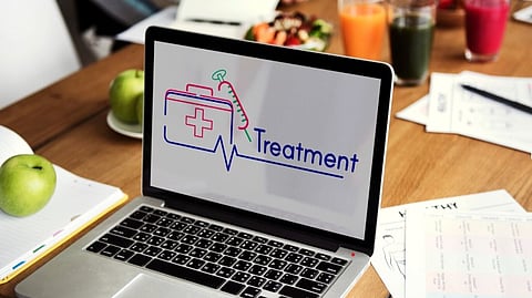 A laptop kept on a table with some papers, drinks and eatables, its screen showing the words treatment.