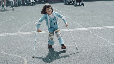 A small girl with restricted movements smiling happily with the walking stick.